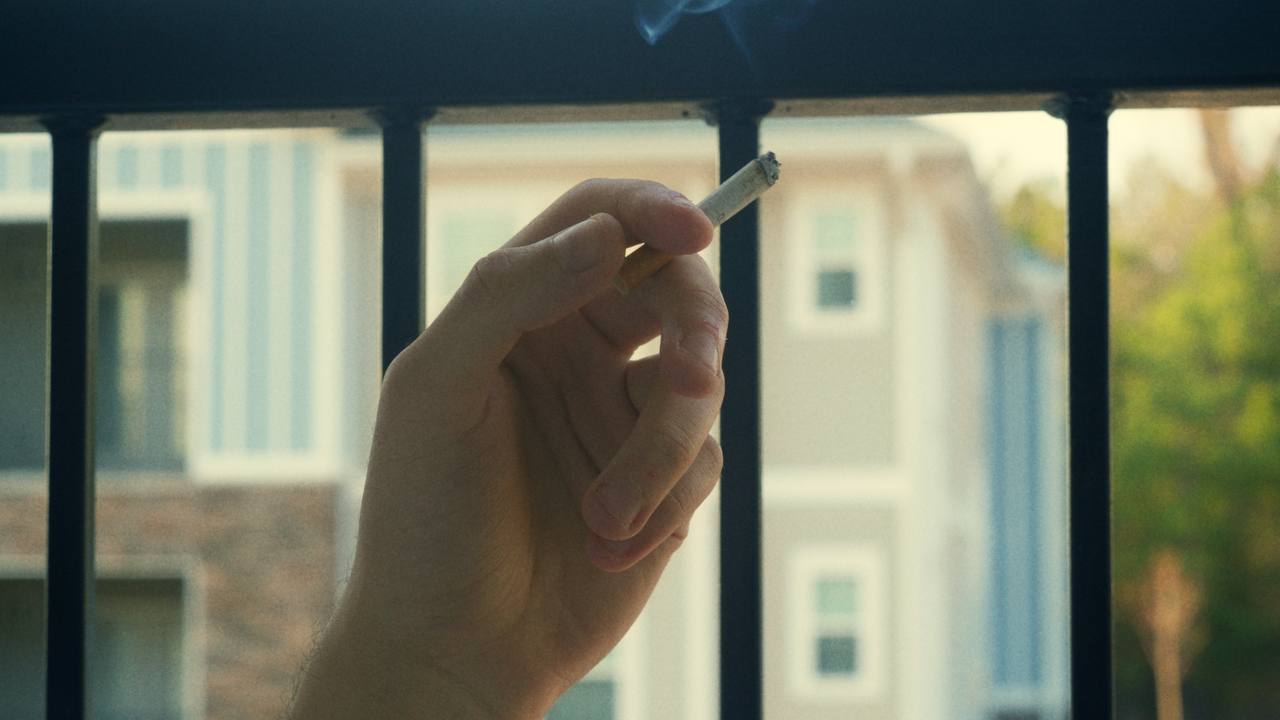 Cigarette smoke rising against a balcony railing
