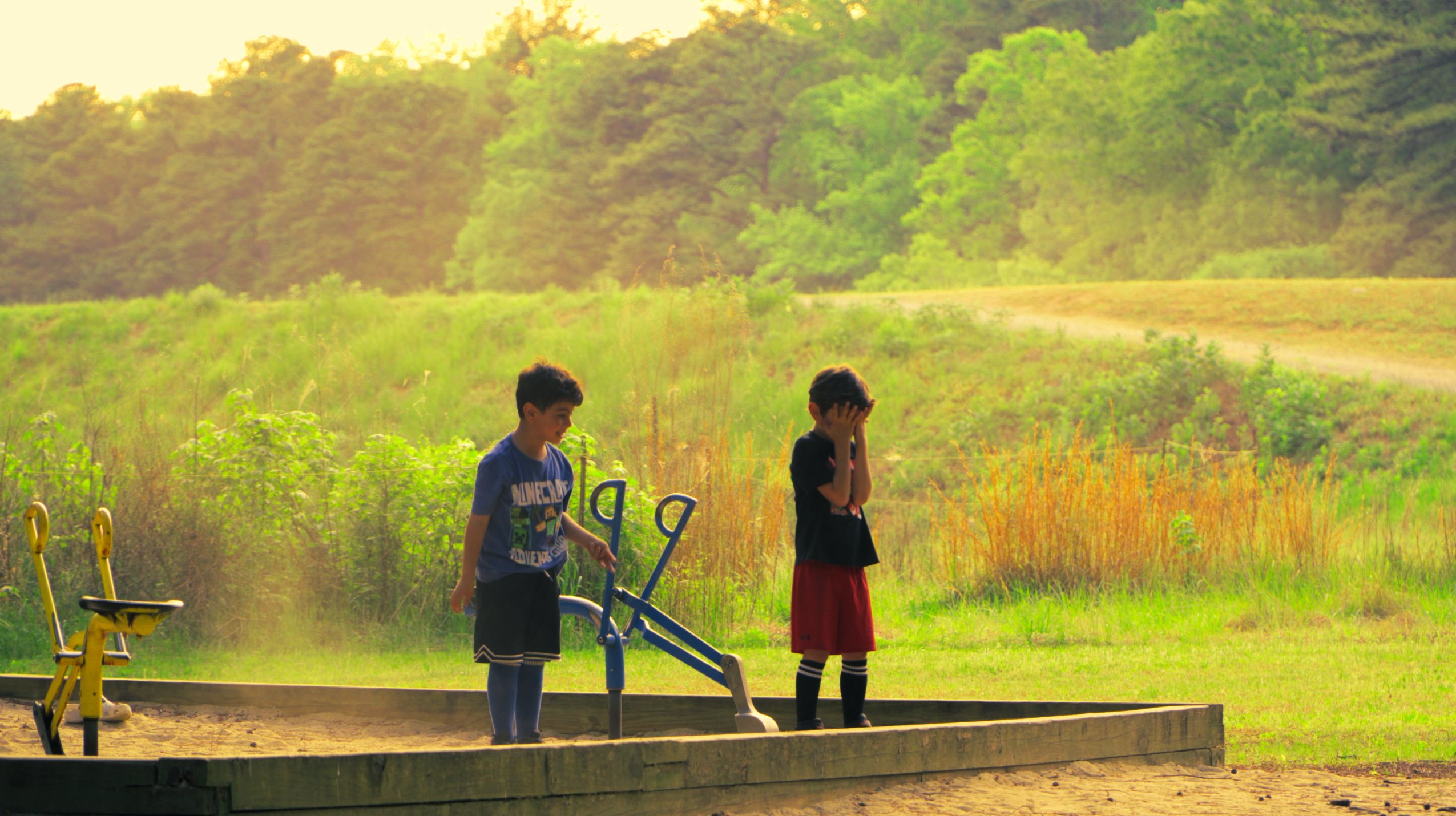 Two boys at a playground at golden hour, color graded